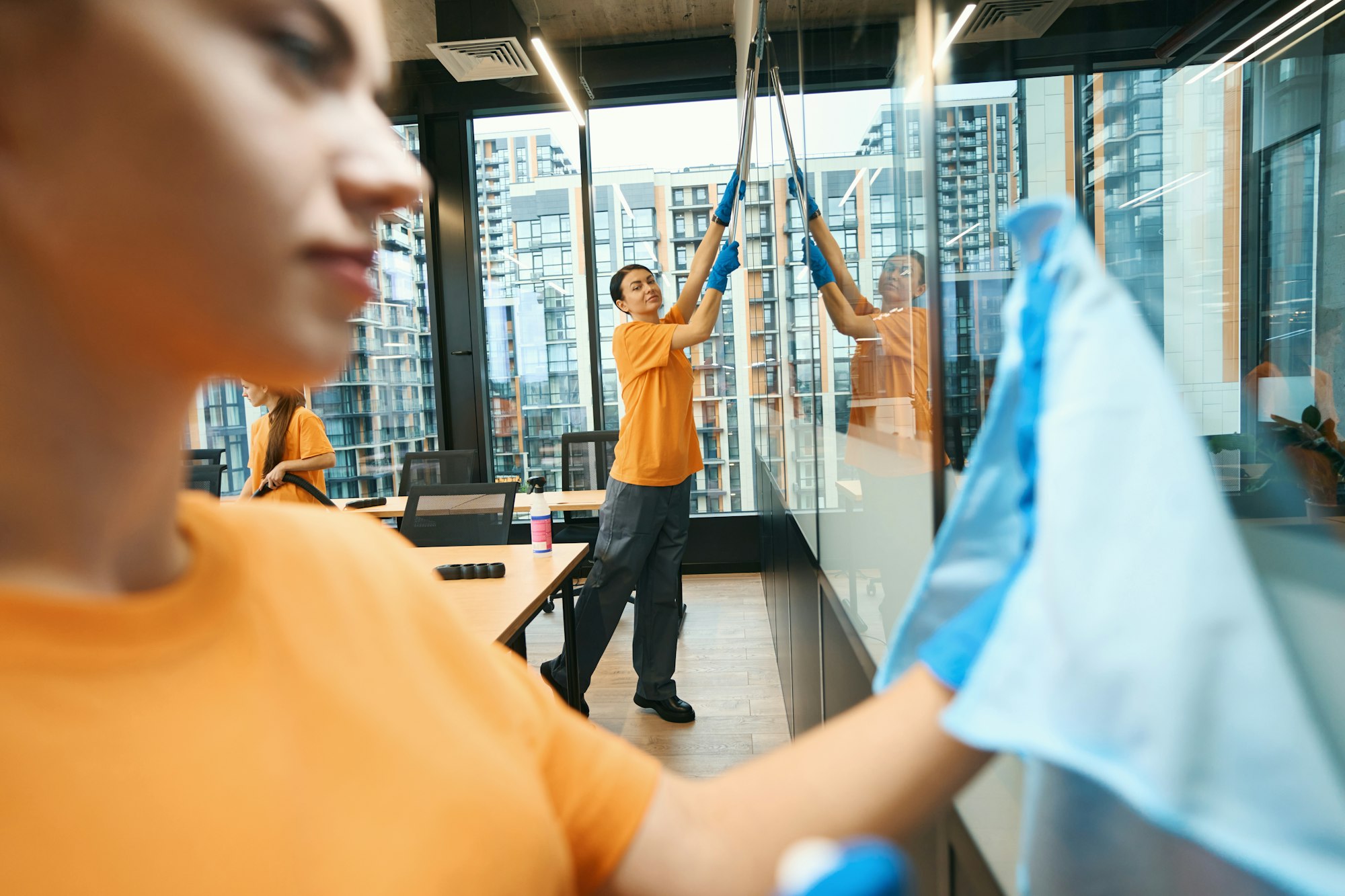 Cleaning company team in overalls cleaning a coworking space